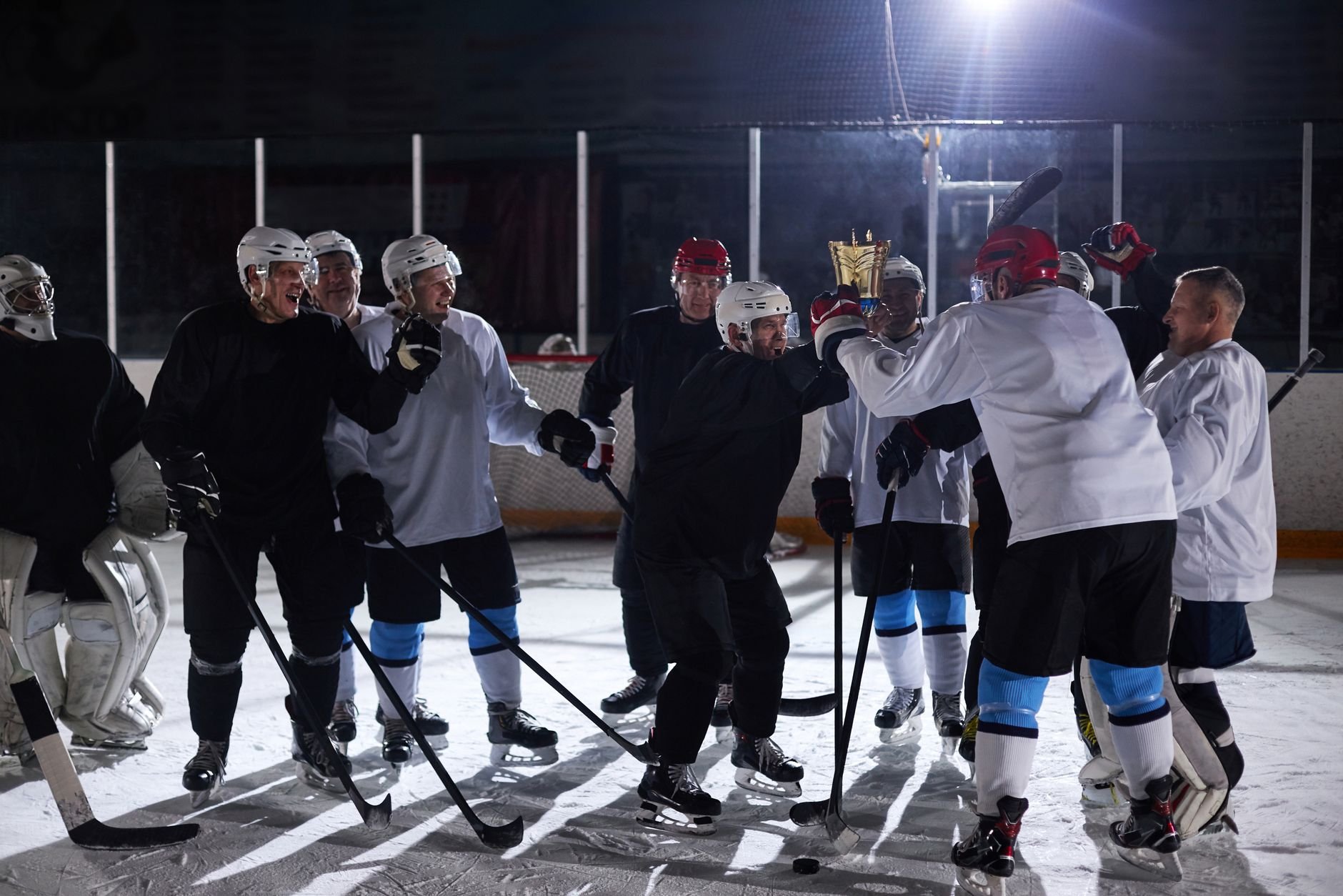 Hockey team celebrating a victory on the ice rink with trophy held high.